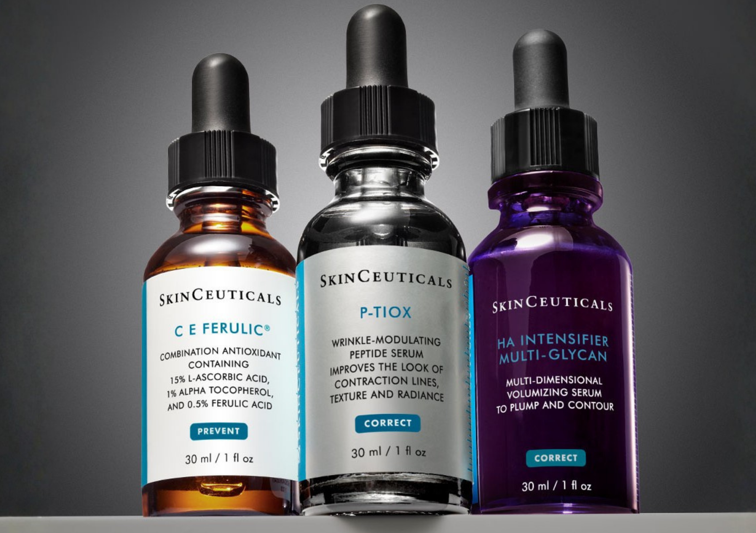Three SkinCeuticals serums with dropper tops (orange, clear, and purple liquids) lined up on a gray background.
